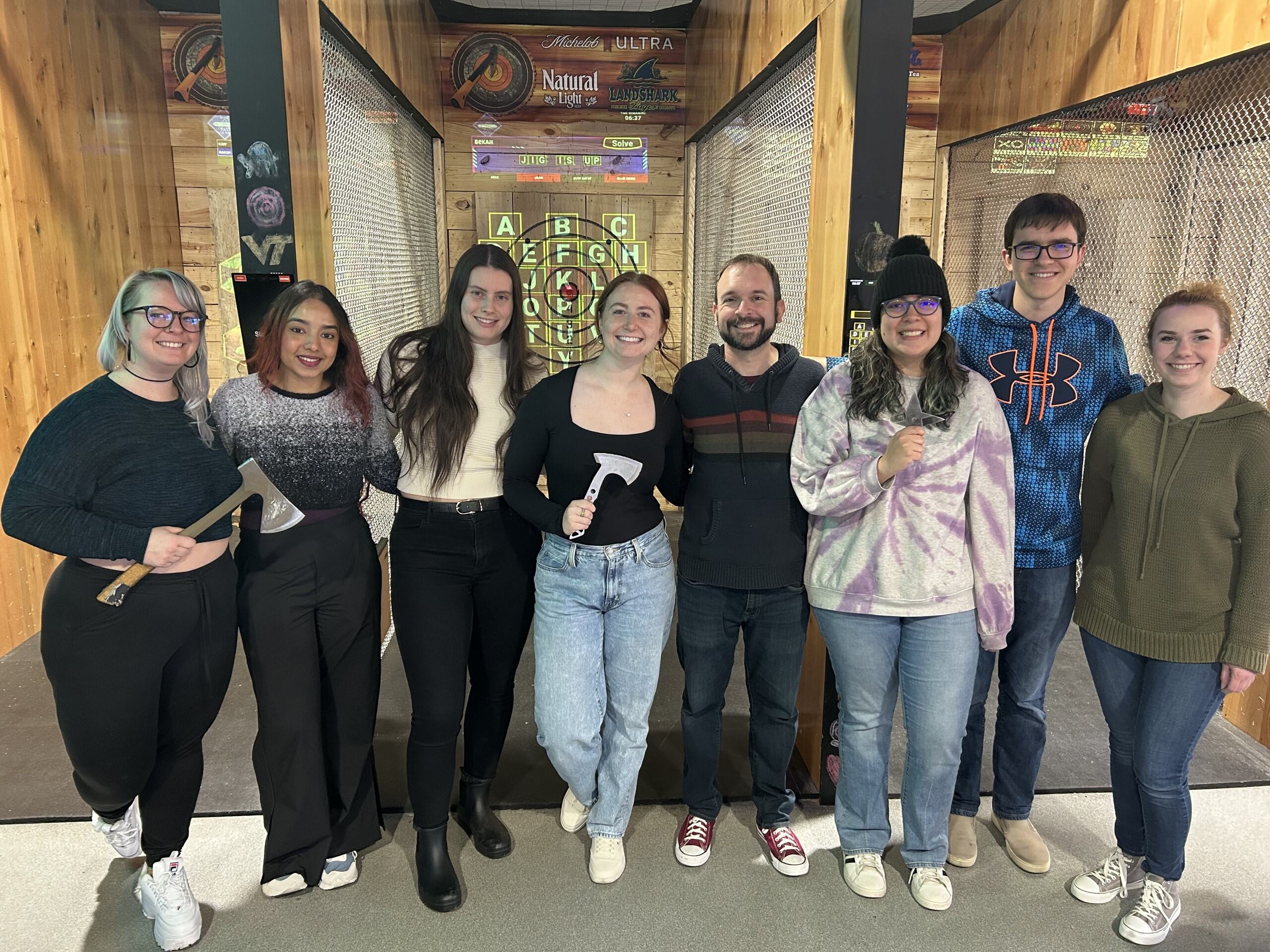A group of guests smiling together in front of the axe-throwing lanes